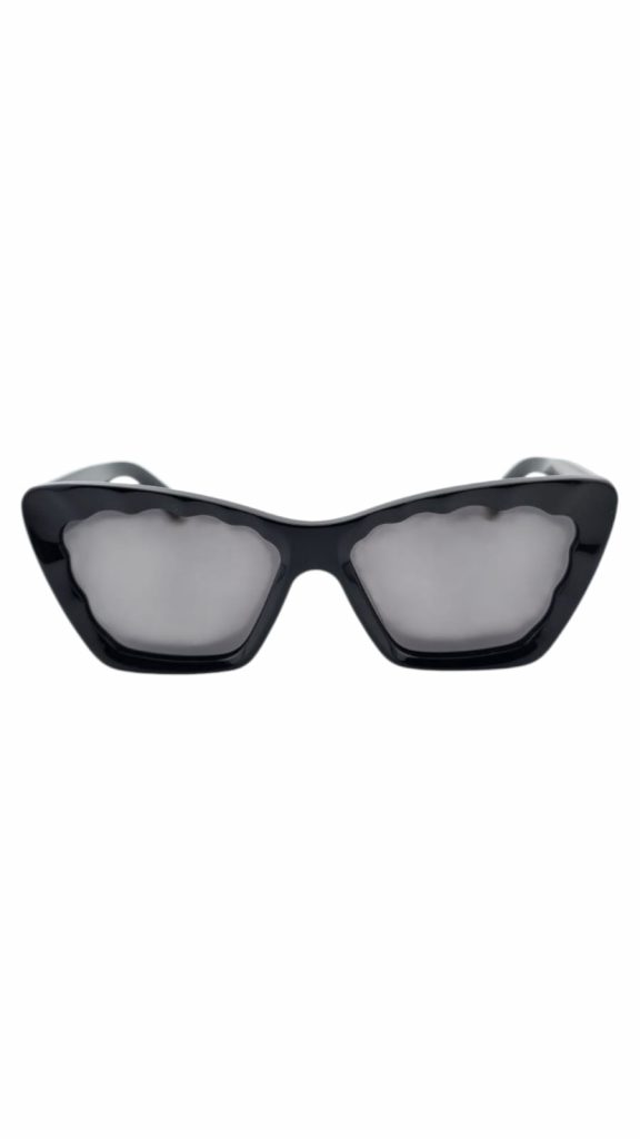 Das Modell Feellens Isabella ist die perfekte Wahl für alle, die ein stilvolles Statement setzen möchten. Die markante Cat-Eye-Form mit gewellter Kontur verleiht dieser Sonnenbrille eine extravagante Note. Der glänzende schwarze Rahmen wird durch goldene Akzente an den Bügelenden raffiniert ergänzt. Gefertigt aus hochwertigem Acetat bietet die Isabella nicht nur optische Raffinesse, sondern auch angenehmen Tragekomfort. Die getönten Gläser dienen als Designmuster – die finale Verglasung erfolgt individuell nach deinen Wünschen, z. B. mit Sonnenschutz, Verlaufstönung oder farblos. Ein echtes Fashion-Piece für stilbewusste Frauen mit Mut zur Form.